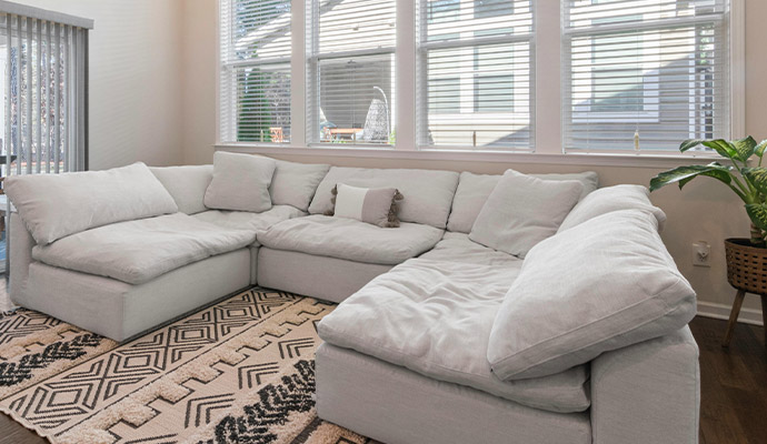 A large, plush light grey sectional sofa arranged on a black and white geometric patterned rug