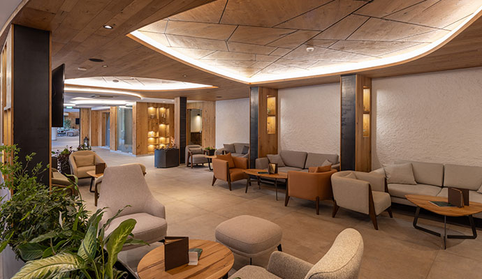 Sleek black lounge chairs and white stools in a modern hotel lobby with polished light wood floors.