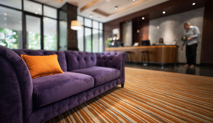 A deep-cleaned purple tufted velvet couch in a high-end hotel lobby.