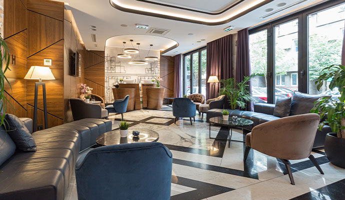A luxury hotel lounge area with deep-cleaned blue velvet chairs and leather sofas in a spotless common area.