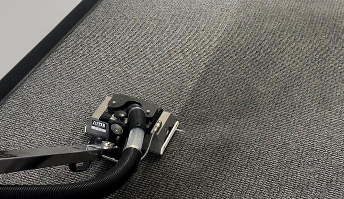 A professional carpet cleaning machine removing stubborn stains from a commercial carpeted floor.