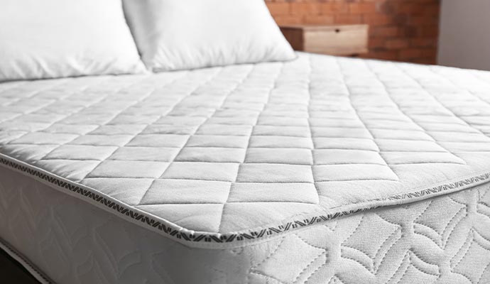 A close-up view of a clean, white quilted mattress top after professional sanitization