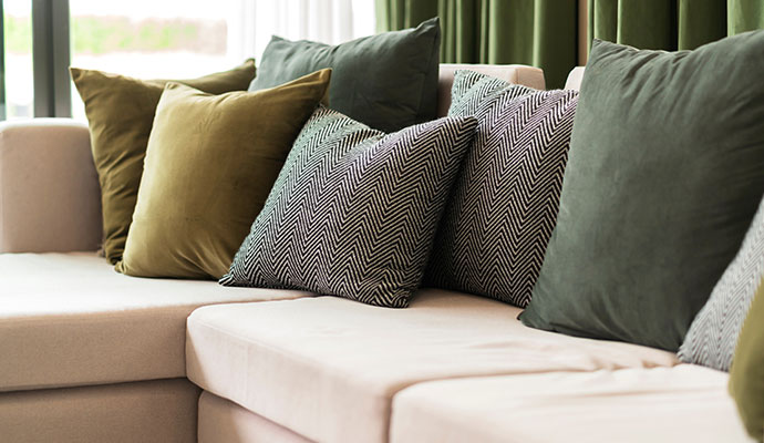 Close-up of green and patterned decorative pillows on a clean beige sofa after professional maintenance.