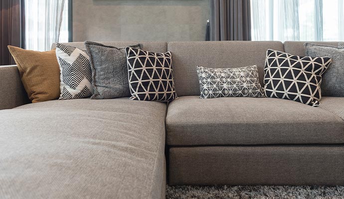 A close-up of a clean, grey sectional sofa with various patterned decorative pillows