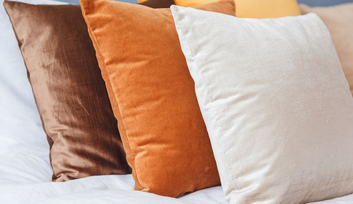 A close-up of brown, orange, and cream velvet loose pillows restored to a soft, clean condition.